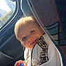 toddler, child, car_interior, window, sunlight, water_bottle, smile, face, clothing, seat, seatbelt, happy, young, person, casual, portrait, daylight, travel, cute, baby