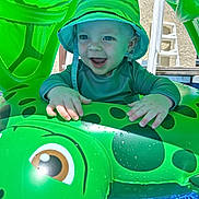 Marty joined the competition — help win amazing prizes! baby, blue_eyes, child, cute, fun, green_hat, hands, happy, inflatable_pool_toy, outdoor, play, pool, smiling, splash, summer, sun_hat, sunlight, turtle, vacation, water
