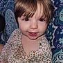 child, toddler, face, smile, brown_hair, floral_shirt, patterned_clothing, indoors, portrait, closeup, cute, young_child, skin, eyes, person, sitting, background_pattern, buttoned_shirt, baby, happy