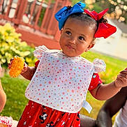 Marcella joined the competition — help win amazing prizes! baby, child, portrait, outdoor, backyard, smiling, happy, hair_bows, red_bow, blue_bow, bib, polka_dots, dress, mickey_mouse, corn_on_the_cob, food, garden, deck, railing, family_gathering