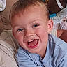 child, boy, smiling, happy, blue_eyes, short_hair, light_blue_shirt, couch, indoor, portrait, close_up, expression, person, toddler, cute, joyful, home, casual_clothing, fun, cheerful