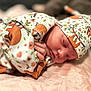 newborn, baby, sleeping, blanket, hat, floral_pattern, fox_pattern, soft_texture, pink, cozy, infant, cute, resting, peaceful, portrait, closeup, child, wrapped, clothing, indoors