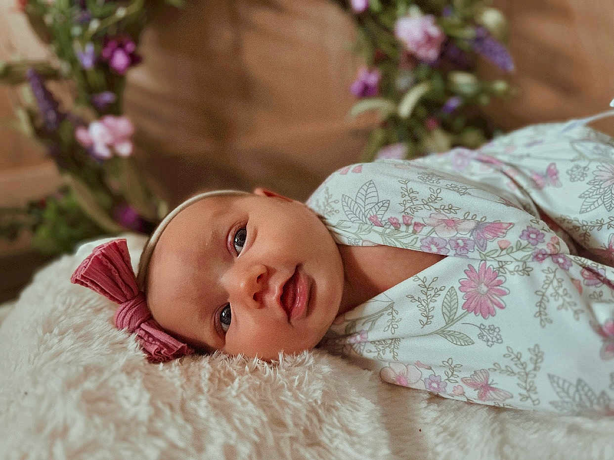 Wrenleigh joined the competition — help win amazing prizes! baby, infant, face, headband, flower, floral_pattern, blanket, soft_texture, cute, lying_down, portrait, indoor, child, closeup, pink, white, decor, young, peaceful, adorable