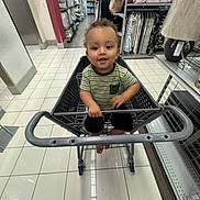 Ezra joined the competition — help win amazing prizes! toddler, shopping_cart, store, aisle, floor_tiles, shelves, bedding, lamp, curious, child, indoor, clothing, striped_shirt, black_shorts, person, smile, shopping, retail, baby, handle