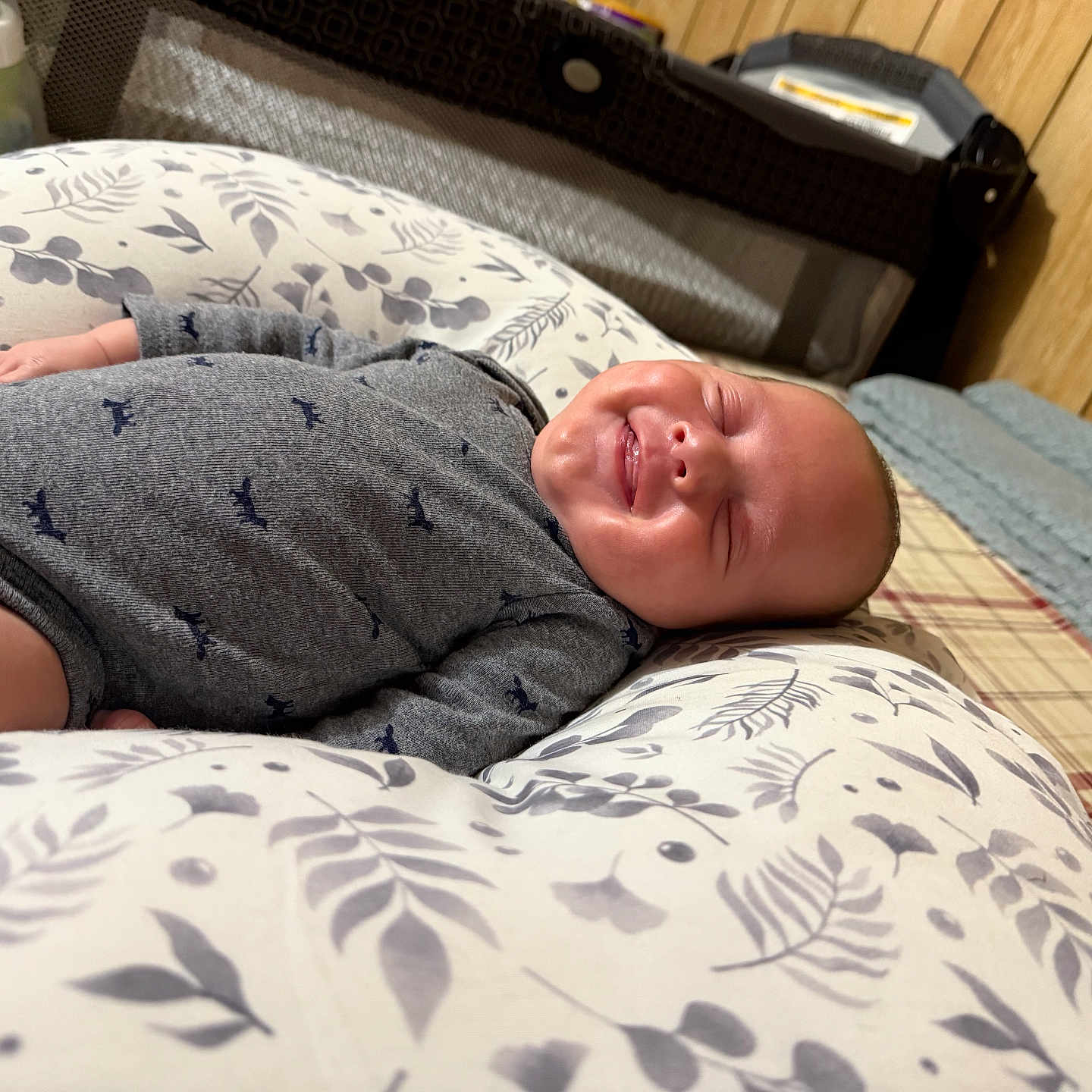 Luca is registered to the contest to win money with this photo: baby, baby_bed, bedroom, bottle, child, cozy, cushion, cute, fabric, floral_pattern, home, indoor, infant, lying_down, onesie, person, sleeping, smiling, soft_lighting, wood_paneling