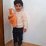 Ilyan participe au concours pour gagner de l'argent avec cette photo : child, toddler, boy, plush_toy, stuffed_animal, sweater, turtleneck_sweater, black_pants, boots, standing, indoor, textured_wall, tile_floor, doorway, portrait, smile, brown_hair, hand, cute, cozy