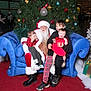 beard, blue_couch, celebration, children, christmas_tree, decorations, family, festive, glasses, holiday, holiday_spirit, indoor, laughing, ornaments, red_carpet, red_dress, santa_claus, shy_child, smiling, winter