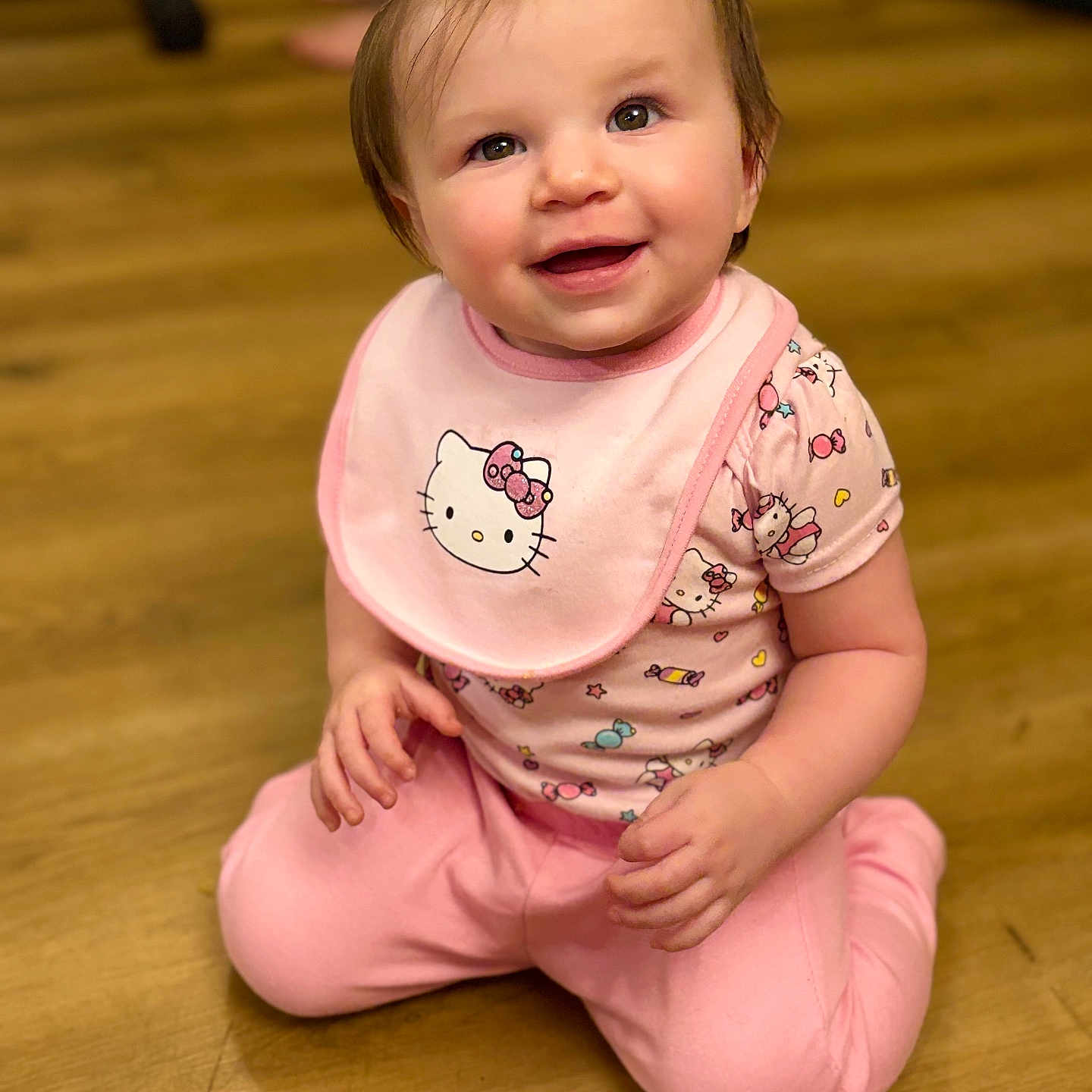 Amethyst Jade joined the competition — help win amazing prizes! baby, bib, brown_eyes, child, chubby_cheeks, cute, hair, hair_bow, hands, happy, hardwood_floor, hello_kitty, indoors, infant, kneeling, onesie, pink_clothing, portrait, sitting, smiling