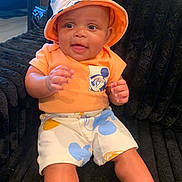 Messiah joined the competition — help win amazing prizes! baby, child, smiling, orange_shirt, bucket_hat, mickey_mouse, shorts, sitting, couch, indoor, cute, happy, portrait, person, infant, headwear, furniture, expression, skin, clothing
