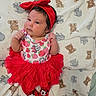 adorable, baby, blanket, child, clothing, cute, elephant_pattern, headband, indoor, infant, lying_down, minnie_mouse, playful, portrait, red_tutu, sock, soft_texture, strawberry_pattern, teddy_bear_pattern, toddler
