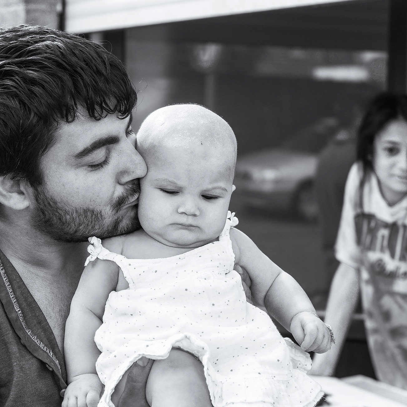 Martocian Leyla participe au concours pour gagner de l'argent avec cette photo : affection, baby, beard, black_and_white, blurred_background, candid, casual_clothing, child, dress, expression, family, holding, kiss, love, man, outdoor, person, portrait, toddler, young_child