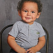 Jorge joined the competition — help win amazing prizes! child, toddler, smiling, curly_hair, grey_shirt, jeans, sitting, chair, portrait, casual_clothing, happy, cute, indoor, studio, young_child, person, face, expression, background, hands