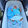 baby, infant, child, stroller, lying_down, blue_clothing, white_clothing, hat, blanket, socks, pacifier, outdoor, portrait, sleeping, awake, open_mouth, hands, bedding, fabric, family