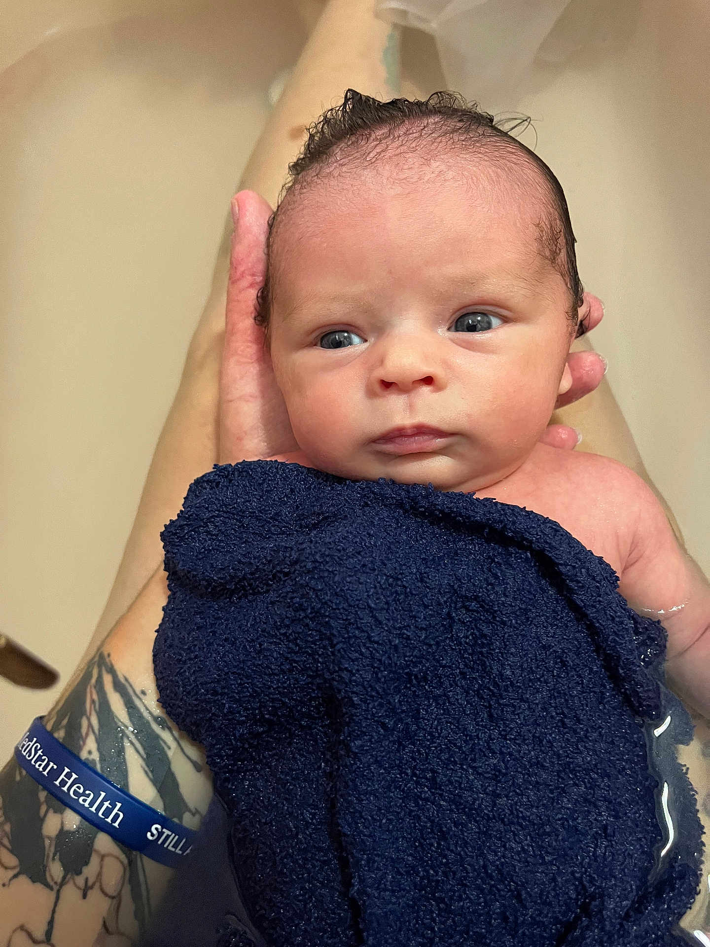 Julianna joined the competition — help win amazing prizes! newborn, baby, infant, bath, towel, water, tattoo, hand, skin, face, blue, person, portrait, wet, cute, expression, newborn_bath, human, closeup, baby_care