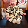 baby, infant, smiling, sitting, headband, clothing, cute, indoor, child, portrait, happy, person, leopard_print, mickey_mouse, apparel, young_child, headwear, blush, cheerful, decorative_text