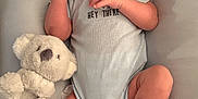 Blake is registered to the contest to win money with this photo: baby, infant, one_month, onesie, stuffed_animal, koala, wooden_plaque, giraffe, soft_surface, cute, newborn, lying_down, hand_gesture, smiling, hair, skin, foot, toe, child, portrait