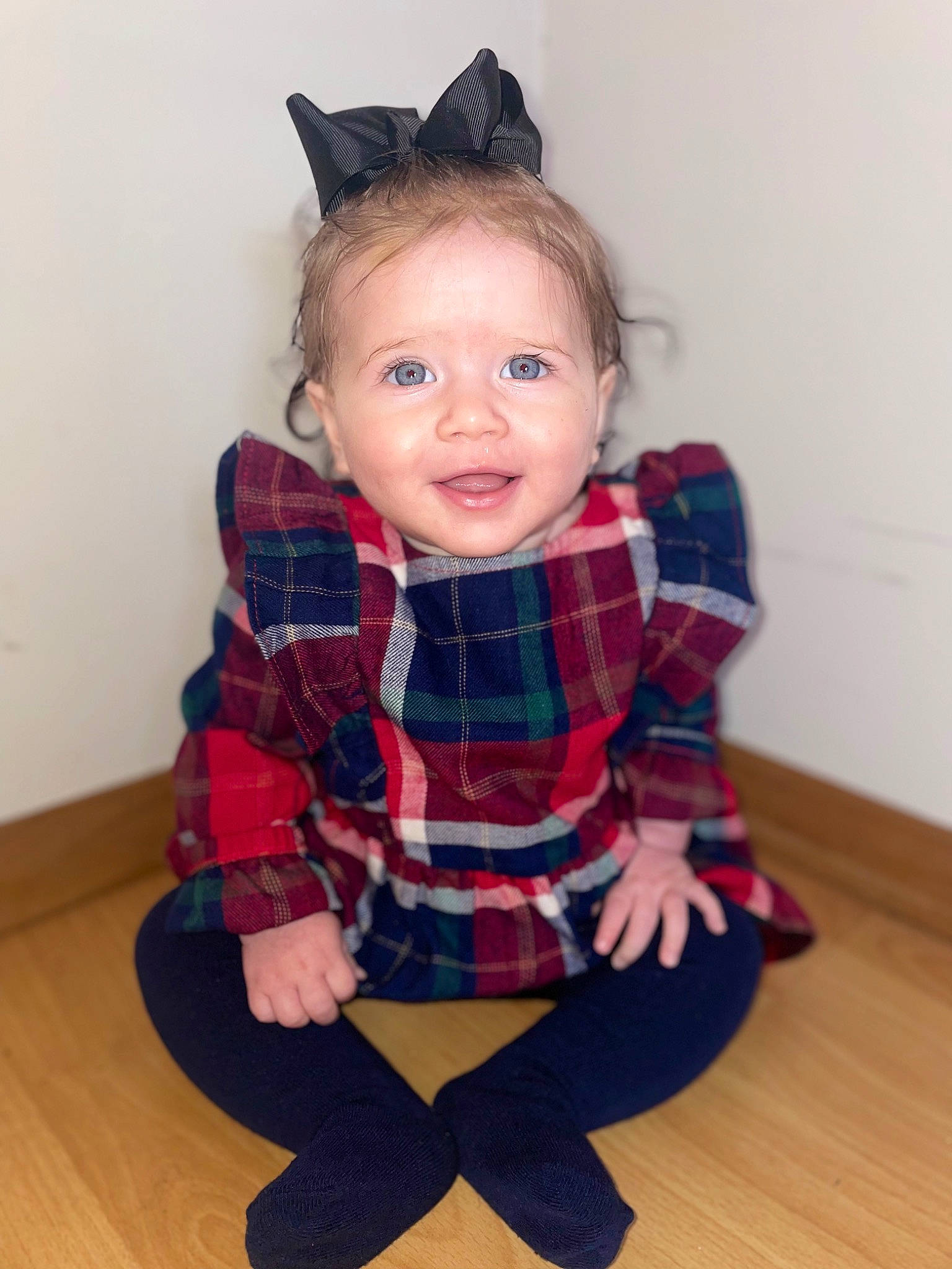 Brynlee is registered to the contest to win money with this photo: arm, baby_toddler_clothing, dress, eye, flooring, hair, human_body, leg, neck, outerwear, person, plaid, shoulder, skin, sleeve, tartan, textile, toddler, toy, waist