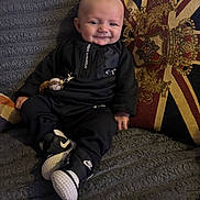 Dream joined the competition — help win amazing prizes! baby, infant, smiling, black_clothing, nike_shoes, under_armour, sitting, couch, blanket, pillow, union_jack, indoor, child, cute, portrait, happy, cozy, home, toy, fashion