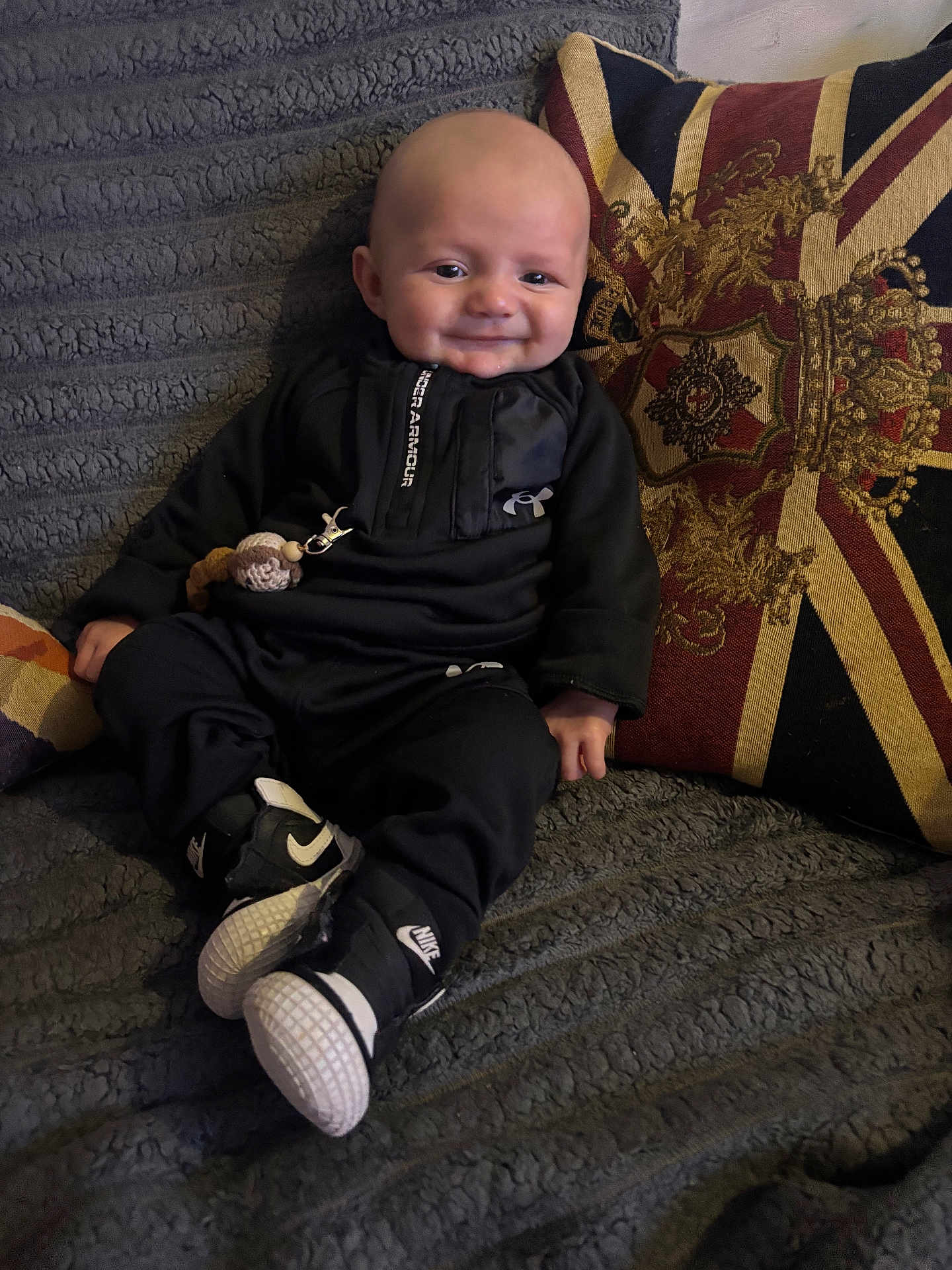Dream joined the competition — help win amazing prizes! baby, infant, smiling, black_clothing, nike_shoes, under_armour, sitting, couch, blanket, pillow, union_jack, indoor, child, cute, portrait, happy, cozy, home, toy, fashion