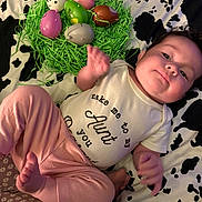Nova joined the competition — help win amazing prizes! baby, child, infant, onesie, pink_pants, plastic_eggs, green_shredded_paper, cow_print_blanket, face, smile, hand, foot, indoor, cute, playful, easter, laying_down, clothing, person, portrait