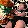 Nova is registered to the contest to win money with this photo: baby, black_onesie, blanket, child, cozy, curious, cute, giraffe, happy, indoor, infant, lying_down, patterned_blanket, playful, plush_toy, reaching, smiling, soft_toy, toddler, young_child