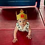baby, child, crawling, burger_king_crown, indoor, playground, red_floor, blue_eyes, curious, cute, infant, paper_crown, clothing, plastic_play_structure, hands, face, looking_up, floor_mat, toddler, person