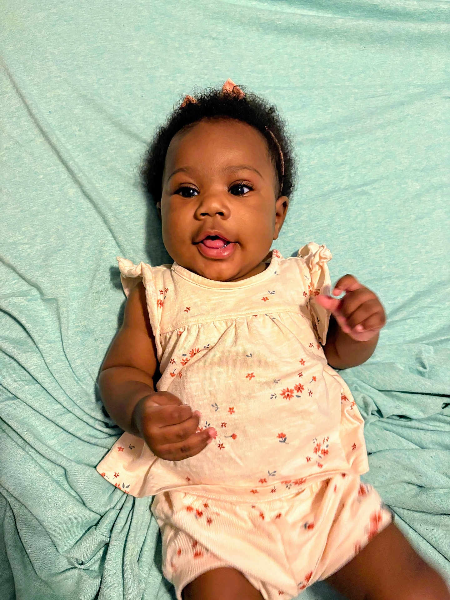 Soni joined the competition — help win amazing prizes! baby, infant, child, smiling, cute, pink_bow, floral_outfit, blanket, lying_down, soft_texture, happy, playful, indoors, portrait, person, young_child, adorable, skin, headband, expression