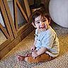 Udayveer is registered to the contest to win money with this photo: baby, barefoot, brown_hair, carpet, child, cute, dark_eyes, floor, indoors, mirror, pants, plant, plant_pot, portrait, pouf, shirt, sitting, smiling, toddler, wood_furniture