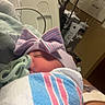 Malia is registered to the contest to win money with this photo: newborn, baby, hospital, blanket, pacifier, bow, hat, arm, medical_equipment, bed, person, infant, sleeping, wrapped, striped, closeup, indoors, care, healthcare, rest