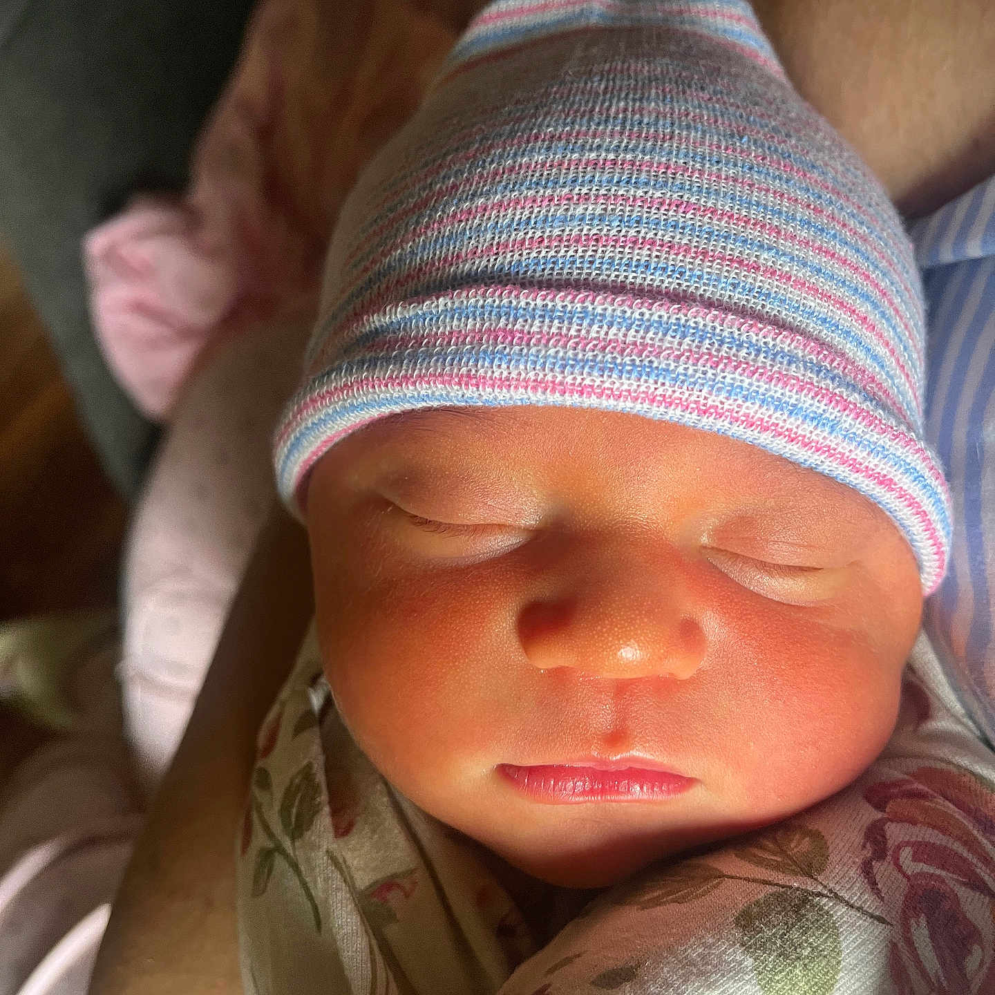 Malia is registered to the contest to win money with this photo: newborn, baby, sleeping, hat, striped_hat, blanket, floral_pattern, close_up, face, person, infant, skin, peaceful, resting, indoors, human, portrait, cute, warm_light, soft_texture
