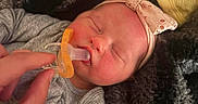 Ivory is registered to the contest to win money with this photo: baby, newborn, pacifier, hand, blanket, headband, sleeping, infant, cozy, soft_texture, pink, gray_clothing, closeup, cute, child, peaceful, resting, tiny, wrapped, indoors