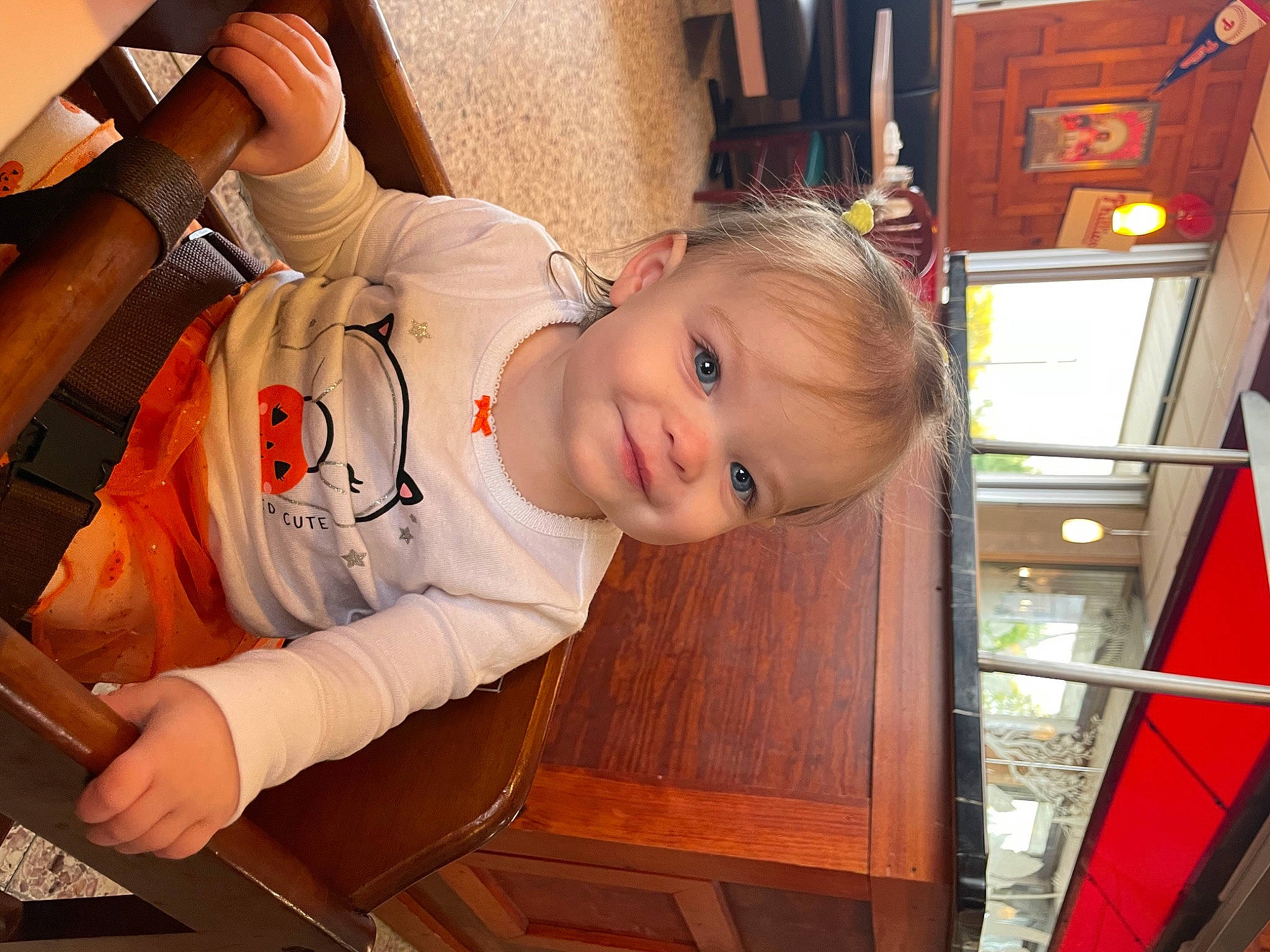 Ellie is registered to the contest to win money with this photo: baby, baby_toddler_clothing, cheek, child, comfort, flooring, fun, happy, joy, orange, person, room, sitting, smile, t_shirt, toddler, vacation, varnish, wood