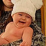 baby, child, woman, glasses, hat, pom_poms, smile, laughing, indoor, person, holding, warm_clothing, face, skin, portrait, happiness, cozy, pointing, headwear, family