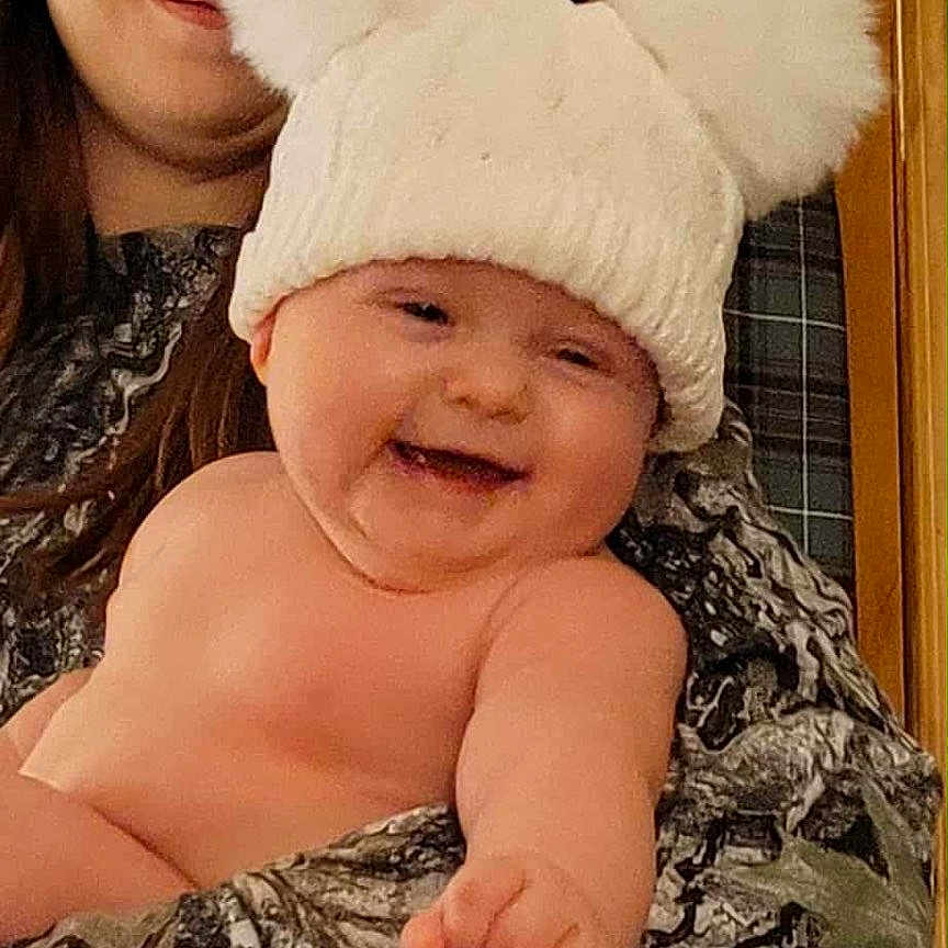 Ivaria is registered to the contest to win money with this photo: baby, child, cozy, face, family, glasses, happiness, hat, headwear, holding, indoor, laughing, person, pointing, pom_poms, portrait, skin, smile, warm_clothing, woman