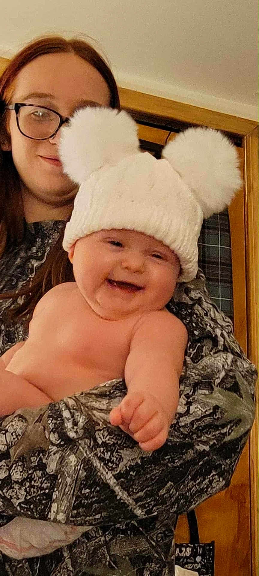 Ivaria is registered to the contest to win money with this photo: baby, child, woman, glasses, hat, pom_poms, smile, laughing, indoor, person, holding, warm_clothing, face, skin, portrait, happiness, cozy, pointing, headwear, family