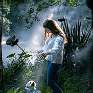 Baby participe au concours pour gagner de l'argent avec cette photo : bandana, casual_clothing, dog, forest, girl, greenery, happy, interaction, jeans, long_hair, mist, nature, outdoor, pet, plants, small_dog, smile, sunlight, walking_path, white_blouse