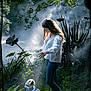 bandana, casual_clothing, dog, forest, girl, greenery, happy, interaction, jeans, long_hair, mist, nature, outdoor, pet, plants, small_dog, smile, sunlight, walking_path, white_blouse