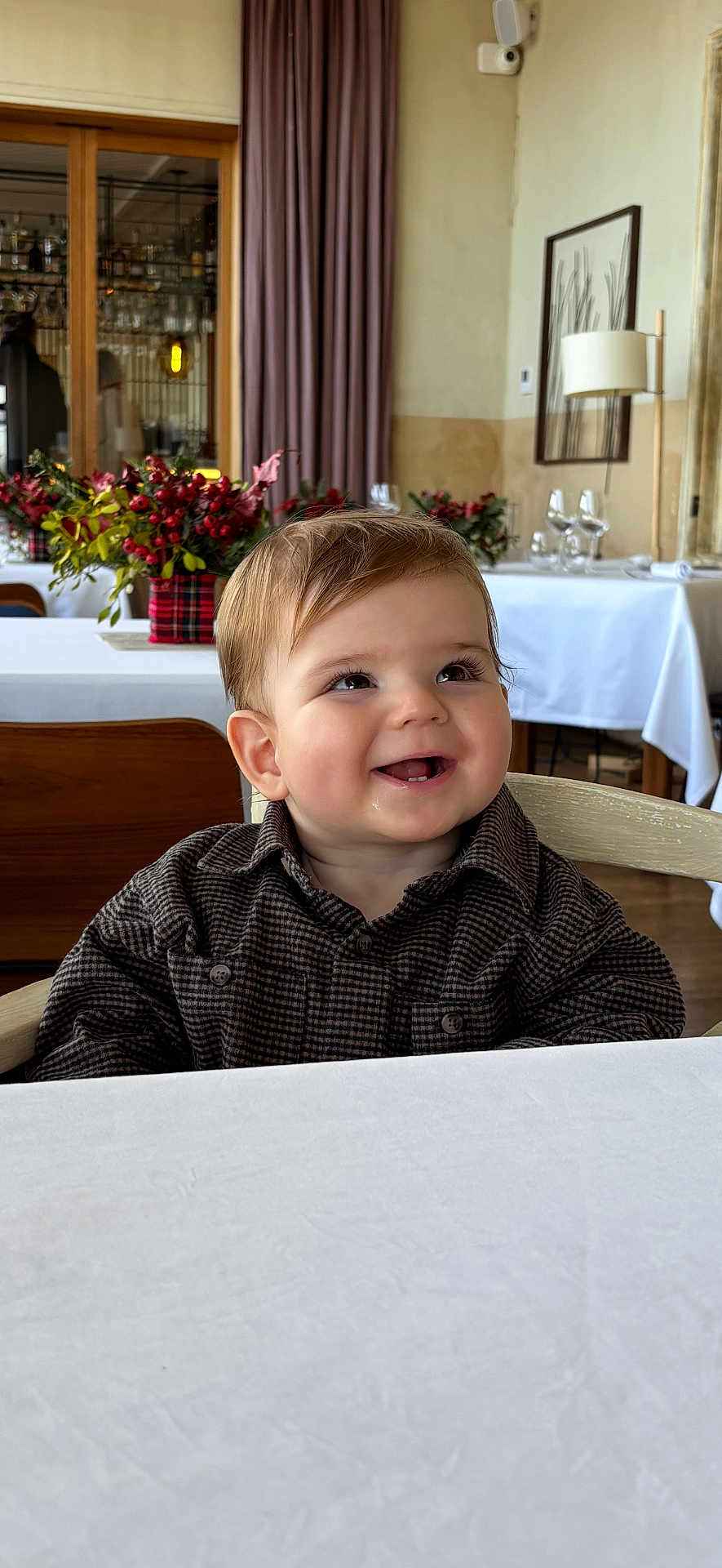 Gaspard participe au concours pour gagner de l'argent avec cette photo : toddler, child, smiling, indoor, restaurant, table, flower_arrangement, curtain, wooden_chair, clothing, face, happy, portrait, baby, furniture, glasses, decor, lamp, window, dining