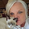 Siam is registered to the contest to win money with this photo: woman, cat, siamese_cat, pet, indoor, couch, blonde_hair, white_shirt, face, eyes, fur, snuggling, closeup, cute, domestic_animal, resting, portrait, feline, animal, companion