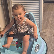 Nova is registered to the contest to win money with this photo: toddler, baby, walker, blue, child, indoor, flooring, wood, door, white, straps, clothing, sitting, foot, hand, expression, person, young, cute, safety