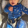 baby, infant, onesie, blue_clothing, baby_seat, cushion, straps, face, eyes, hand, legs, footwear, indoors, cute, child, portrait, expression, comfortable, baby_boy, closeup