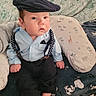 Henry is registered to the contest to win money with this photo: baby, child, infant, blue_shirt, suspenders, black_pants, flat_cap, cushion, patterned_blanket, snoopy, indoor, cute, portrait, sitting, footwear_free, hand, face, fashion, clothing, relaxed