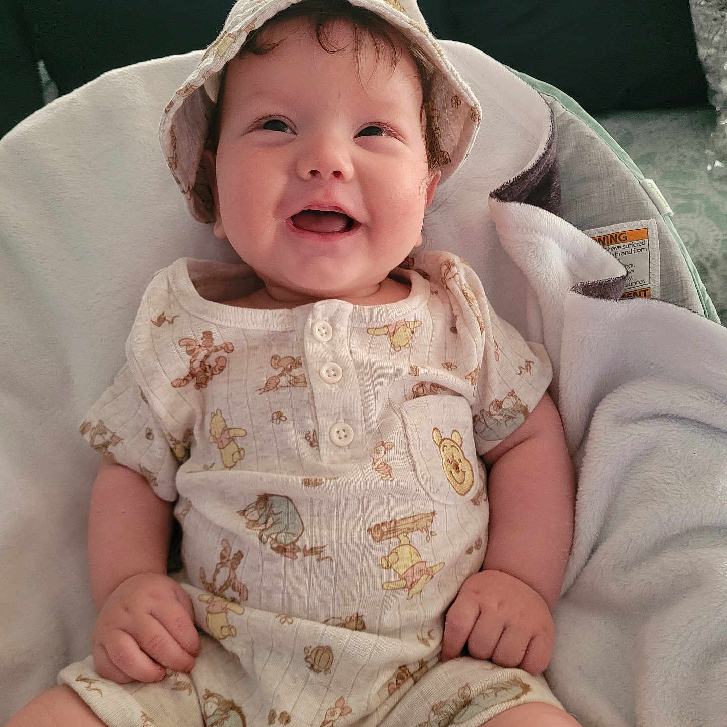 Henry is registered to the contest to win money with this photo: baby, child, hat, smile, happy, clothing, onesie, blanket, infant, cute, sitting, winnie_the_pooh, soft, indoor, portrait, person, baby_clothes, closeup, adorable, young