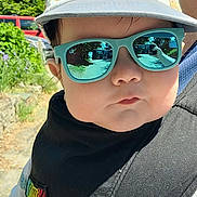 Henry joined the competition — help win amazing prizes! baby, child, sunglasses, hat, cap, outdoor, sunny, reflection, face, person, black_bib, carrier, dinosaur_pattern, portrait, closeup, casual, daylight, fashion, accessory, cute
