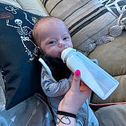 Ryder is registered to the contest to win money with this photo: baby, blanket, bottle, clothing, comfort, couch, cute, face, feeding, hand, indoor, infant, milk, nail_polish, person, pillow, relaxation, soft, tattoo, toddler
