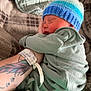 Ryder is registered to the contest to win money with this photo: newborn, baby, sleeping, hat, knitted_hat, onesie, arm, tattoo, hospital_wristband, blanket, patterned_blanket, closeup, indoor, cozy, rest, infant, person, soft_lighting, cute, sleep