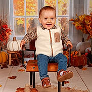 Antoine a rejoint le concours — aidez-le/la à gagner de superbes lots ! toddler, child, smiling, chair, pumpkin, autumn, fall_leaves, pine_cone, window, plaid_shirt, fleece_vest, jeans, brown_shoes, indoor, seasonal_decor, happy, portrait, studio, orange, cozy