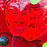 child, face, red, plastic, heart_shape, fist, smile, reflection, distortion, toy, colorful, closeup, happy, portrait, young, cheerful, glossy, translucent, background, playful
