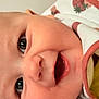 baby, close_up, face, eyes, mouth, bib, strawberry_pattern, infant, skin, cheeks, expression, happy, cute, child, person, portrait, newborn, clothing, smile, head