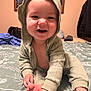baby, child, smiling, hooded_clothing, bed, blanket, hand, foot, indoors, portrait, cute, person, infant, happy, skin, clothing, sitting, room, cozy, casual